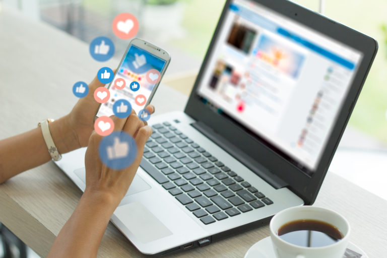 Social Media für den Mittelstand, eine Frau sitzt mit Handy an einem Laptop